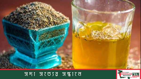 কাচের গ্লাসে ভেজানো হালকা বাদামী রঙের জিরা পানি এবং পাশে কয়েকটি গোটা জিরা রাখা।